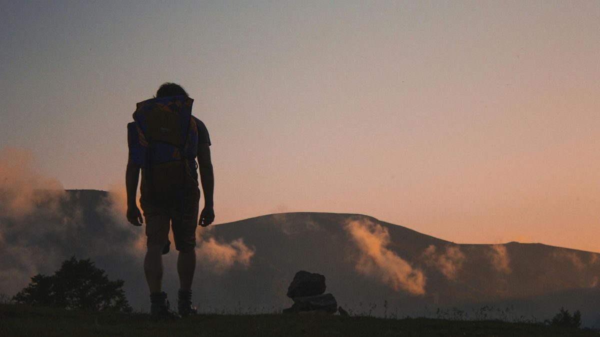 a person standing on a hill looking at a mountain